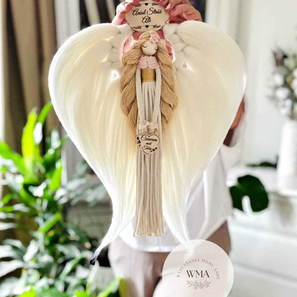 Duża personalizowana dekoracja ścienna Anioł Stróż z makramy - figurka aniołka z długimi beżowymi włosami w różowym sweterku z różyczką i złotym paskiem ze kremową suknia z frędzli i drewnianym sercem z napisem Czuwam nad Tobą, ogromne białe skrzydła w kształcie serca z plecionej wełny, drewniana tabliczka z imieniem, wyjątkowy prezent dla dziewczynki na urodziny komunię lub chrzest, handmade