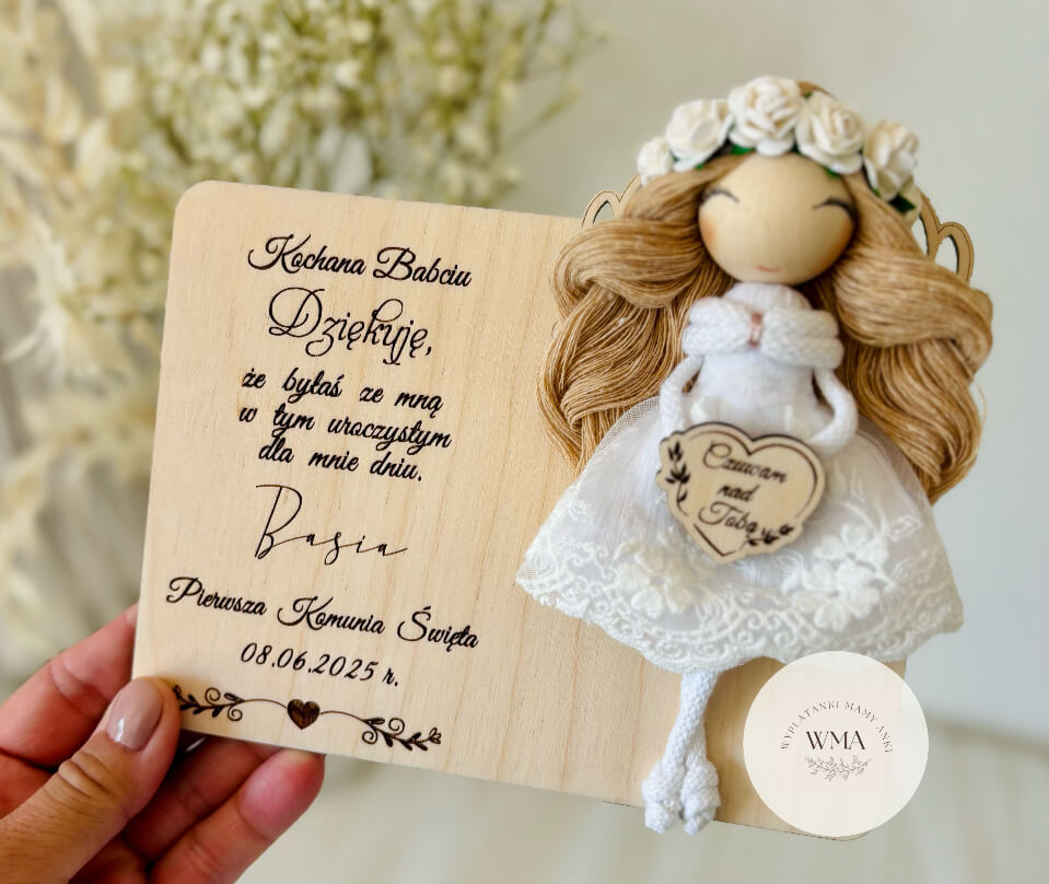Ręcznie robiony aniołek komunijny z makramy w białej sukience z koronki i wiankiem z białych róż, osadzony na personalizowanej drewnianej tabliczce z podziękowaniem dla babci za Pierwszą Komunię Świętą, wyjątkowy prezent komunijny