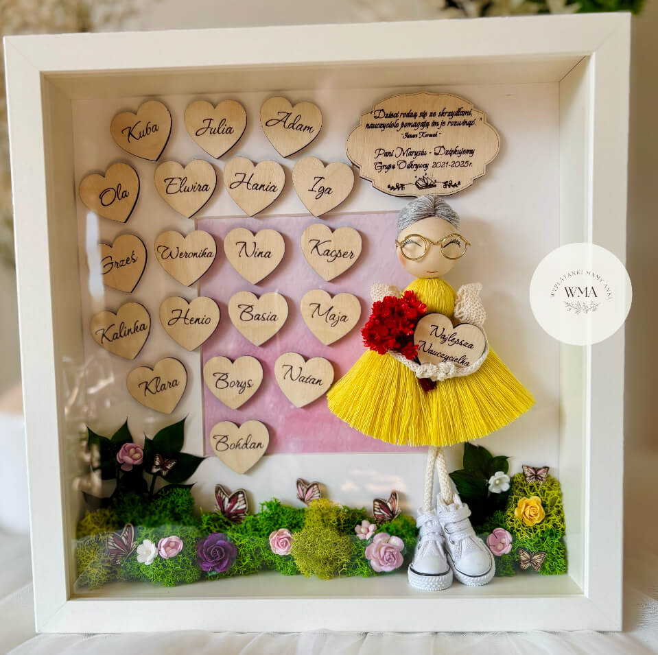 Personalizowana drewniana ramka z podziękowaniem dla nauczyciela z ręcznie robianą laleczką w żółtej sukience z frędzlami i okularach trzymającą czerwony bukiet i serduszko Najlepsza Nauczycielka, drewniane serduszka z imionami dzieci z grupy, dekoracja z mchu, kwiatów i motyli, wyjątkowy prezent od całej klasy
