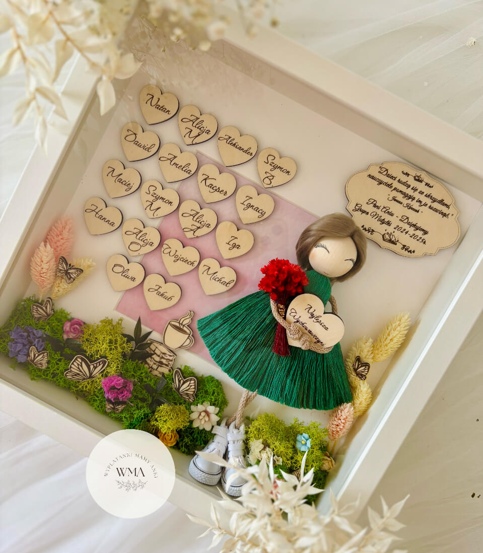 Personalizowana drewniana ramka z podziękowaniem dla wychowawczyni z ręcznie robianą laleczką z brązowymi włosami w zielonej sukience z frędzlami trzymającą czerwony bukiet i serduszko Najlepsza Wychowawczyni, drewniane serduszka z imionami dzieci z grupy, dekoracja z kolorowego mchu, suszonych kwiatów i motyli, wyjątkowy prezent na zakończenie roku szkolnego