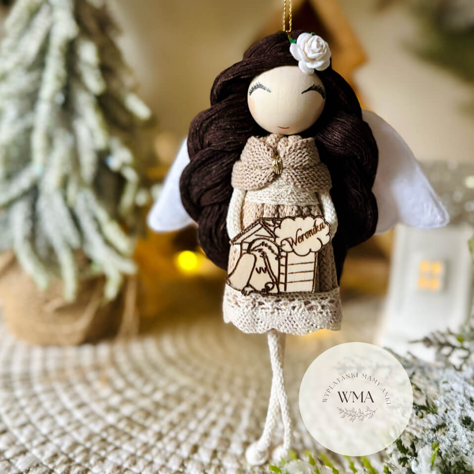 Beżowy aniołek z makramy z ciemnymi włosami i białą różyczką, trzymający personalizowaną zawieszką z pieskiem i imieniem – unikalny prezent handmade WMA