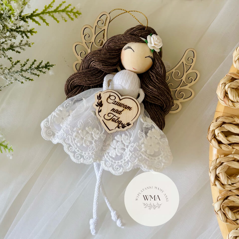 Biały aniołek z makramy z ciemnymi włosami w koronkowej sukience z drewnianym sercem z napisem Czuwam nad Tobą – handmade prezent WMA