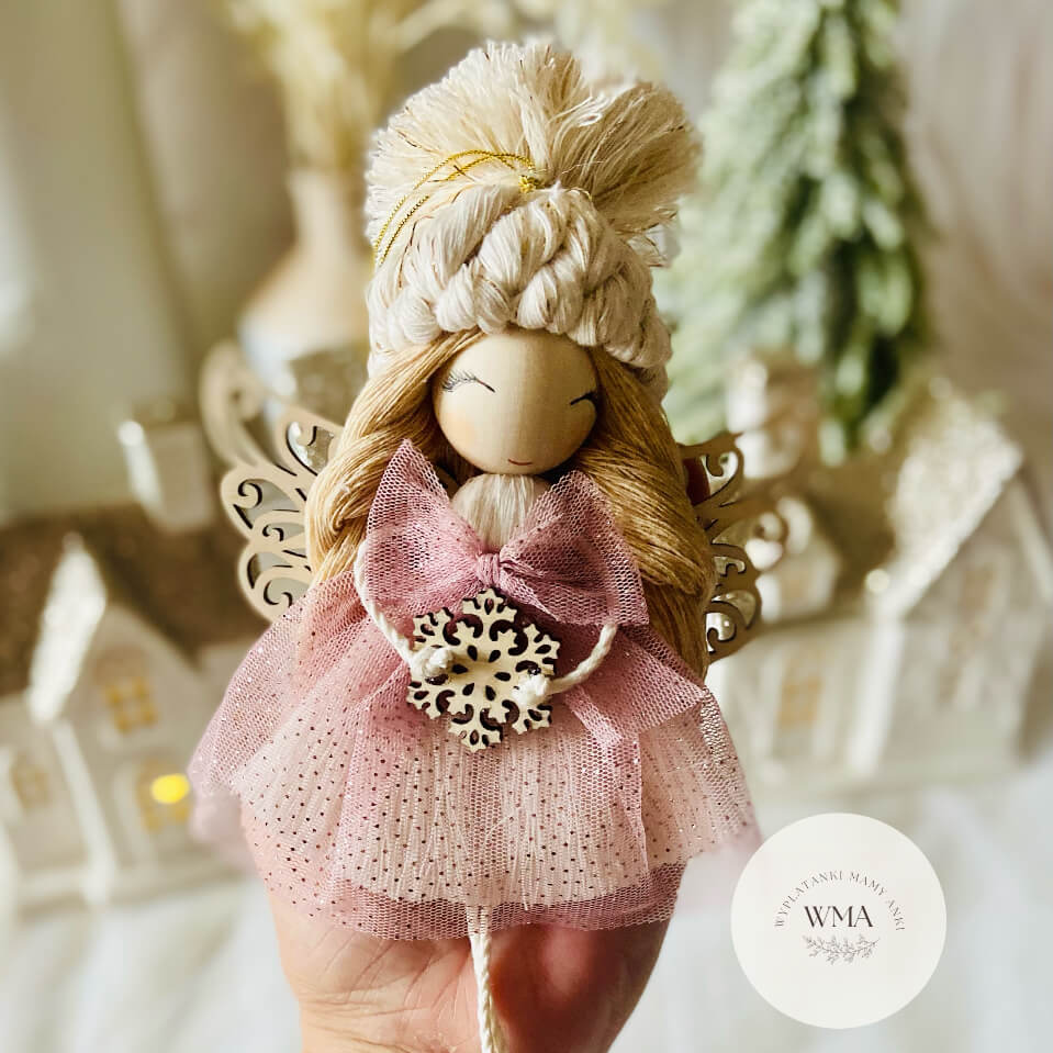 Różowy aniołek z makramy z blond włosami, ażurowymi drewnianymi skrzydłami i płatkiem śniegu - ozdoba świąteczna handmade WMA
