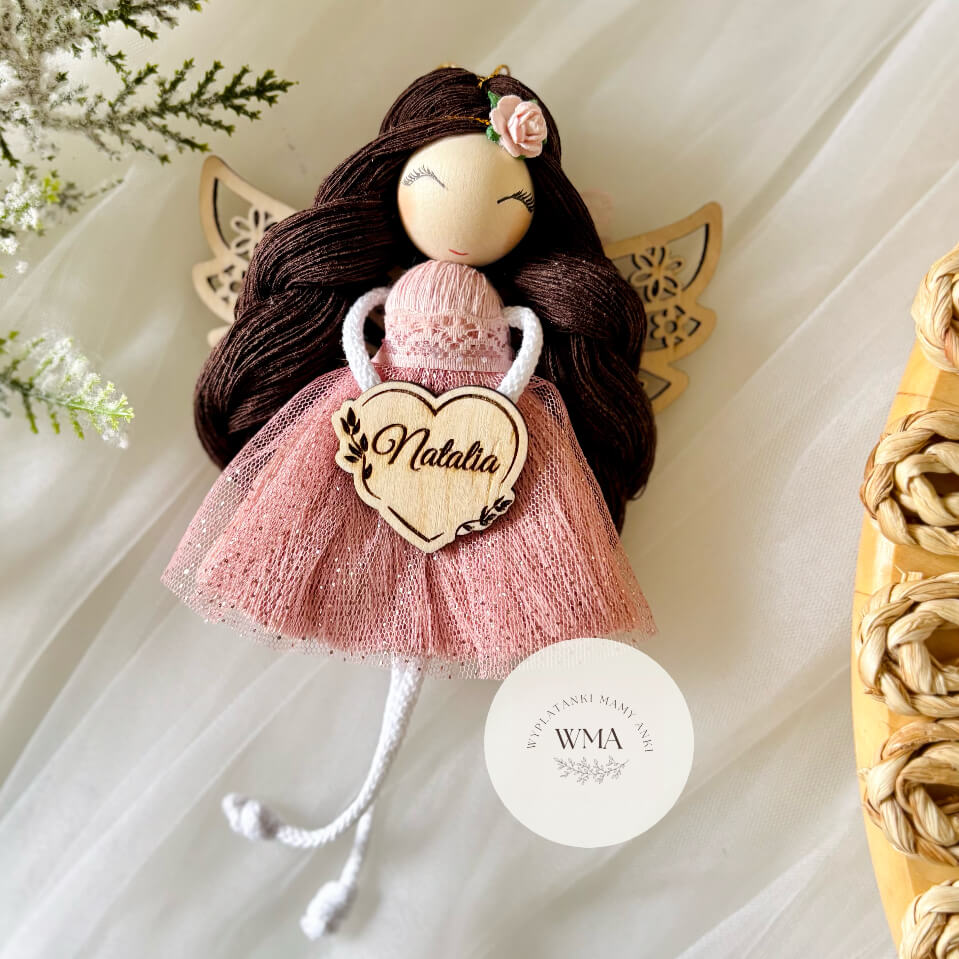 Różowy aniołek z makramy z ciemnymi włosami i różyczką we włosach, trzymający personalizowane drewniane serce z imieniem – handmade prezent WMA