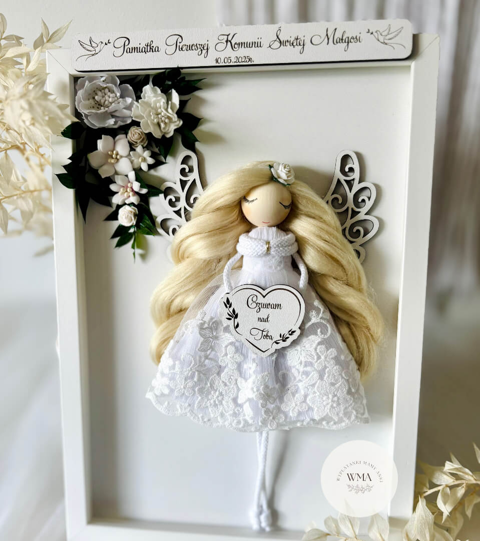 Pamiątka Pierwszej Komunii Świętej Małgosi – aniołek z długimi blond włosami w białej koronkowej sukience z białymi kwiatami i drewnianymi skrzydłami