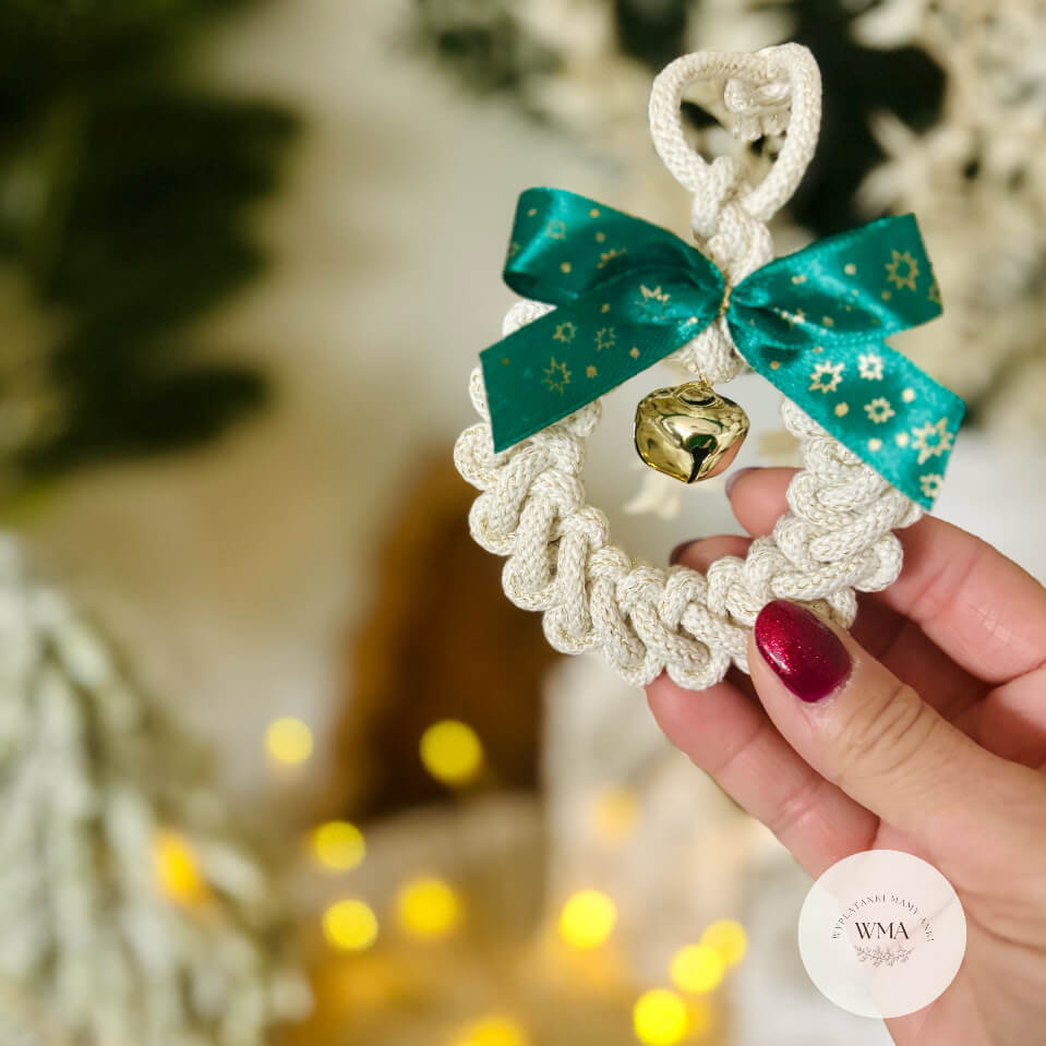 Świąteczny wianek makramé w kolorze ecru z zieloną wstążką w złote gwiazdki i złotym dzwoneczkiem – ozdoba choinkowa handmade WMA